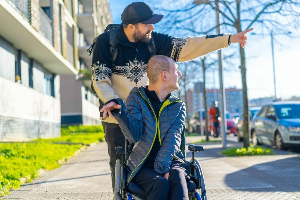 A person with a disability in a wheelchair with a friend walking around having fun, normality
